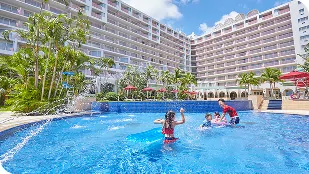 青いタイル張りの屋外プールで、親子が水しぶきを上げて笑顔で夏のファミリー向け旅行を楽しんでいます。