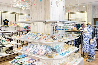 白木目調の支柱を囲む多段棚に、沖縄の風景を写したポストカードや色鮮やかな雑貨が整然と並べられています。