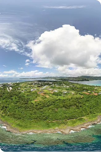 エメラルドグリーンの浅瀬が広がる海岸線から、緑豊かな森と点在する建物が沖縄北部の美ら海水族館周辺まで続いています。