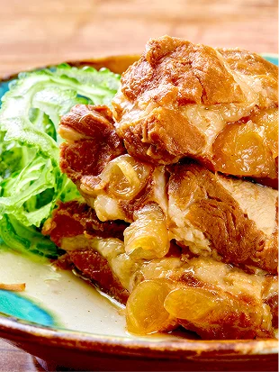 飴色に煮込まれた豚の角煮が皿の中央に積み重なり、鮮やかな緑色の薄切りゴーヤーが彩りを添えています。