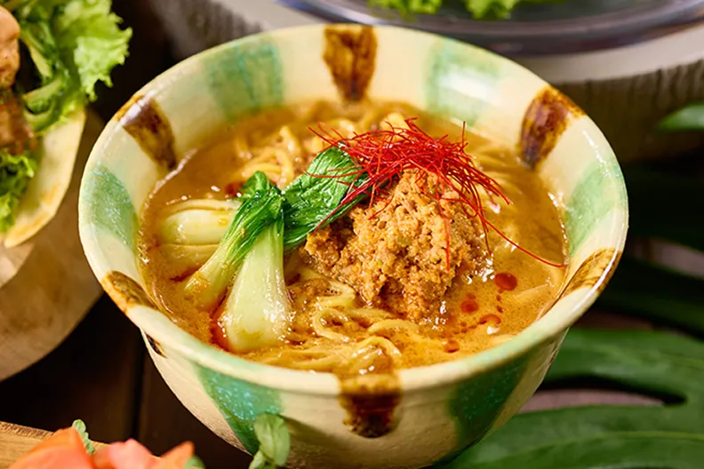 緑と茶色の刷毛目模様が施された陶器鉢に、担々麺のひき肉と青梗菜が盛り付けられ、鮮やかな糸唐辛子が添えられています。