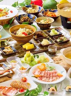 白磁の皿に並ぶ薄切りの肉料理や沖縄そば、多彩な小鉢がテーブルを埋め尽くし、上部からの光が料理の艶を照らしています。