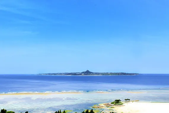 透明度の高い遠浅の海が広がり、水平線上に伊江島の城山が浮かぶ本部半島の海岸線です。